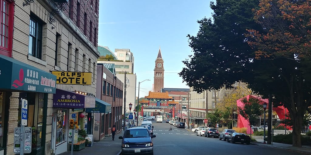 Chinatown - International District view down King Street toward the King Street Station tower with blue skies and a tree shading the street