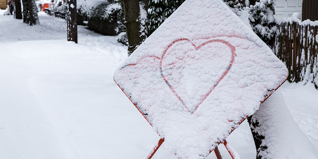 snow covered road sign with heart drawn on it
