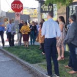 dozen people standing on street corner having a discussion