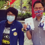 two people in masks holding up census information at outside table