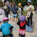 adults and children interacting at skate park