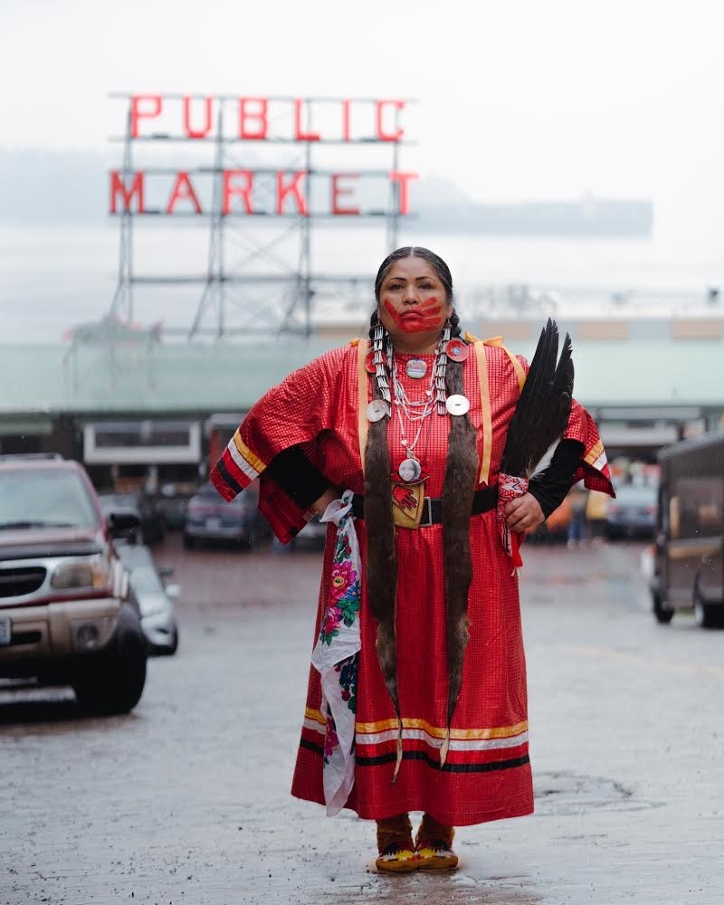 Roxanne White, standing in front of Public Market sign, dressed in red with red hand painted on face