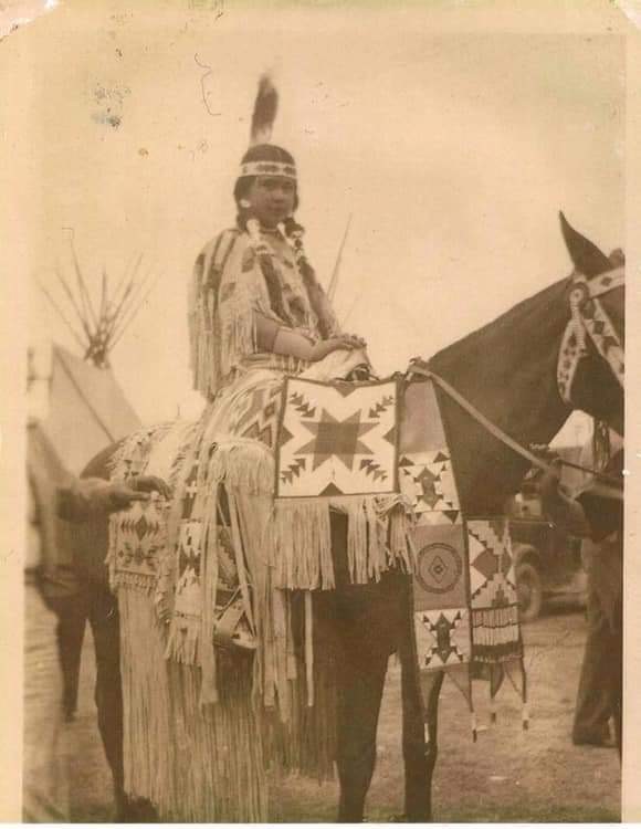 archival photo of young woman on horse in full traditional Nimiipuu regalia