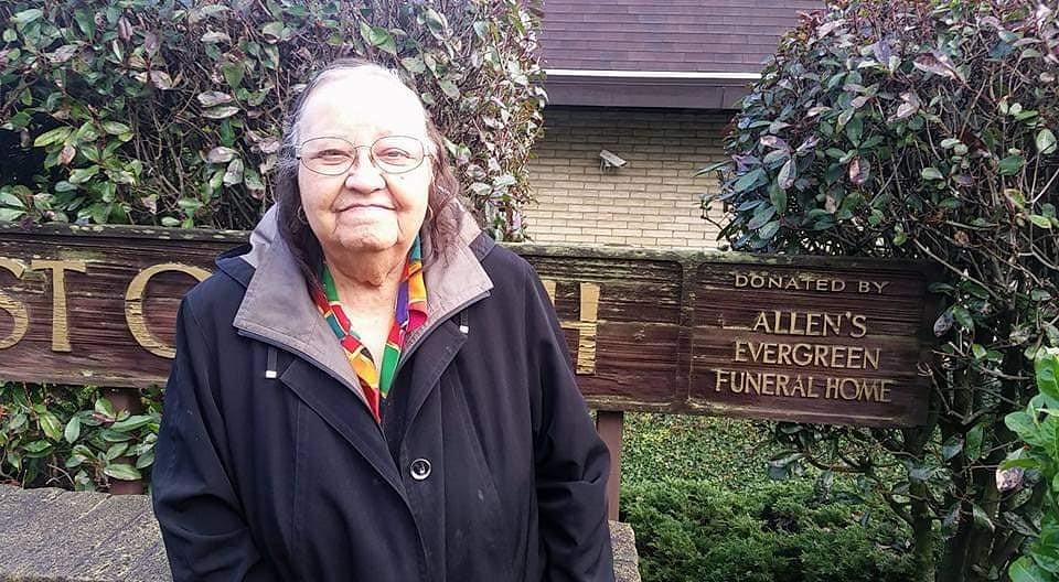 older woman, smiling proudly, while standing in front of Mount Zion Baptist Church sign