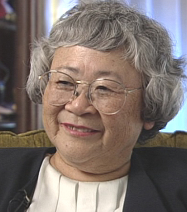 older Japanese woman with gray hair and glasses, smiling.