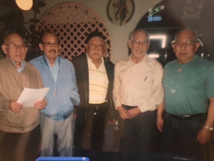 five Latino men posing for a photo in a restaurant