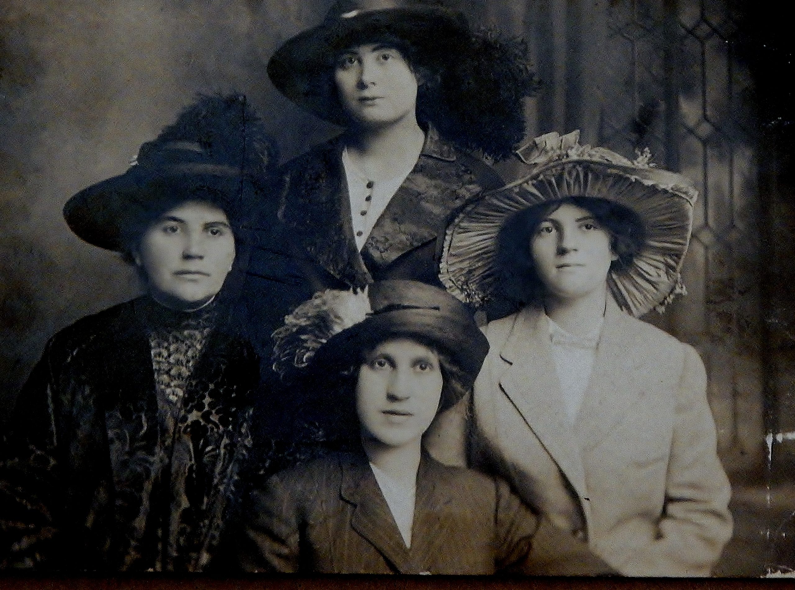 vintage black and white photo of four women in formal dress and hats sitting for a portrait