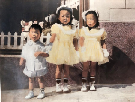 Colorized photo of the author (age 4) and her brother and sister dressed in full ruffles and easter regalia with bobby socks, white shoes, bonnets and white gloves. The youngest, Eddie, is walking toward the camera.