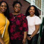 Four Black women, standing in a line, smiling