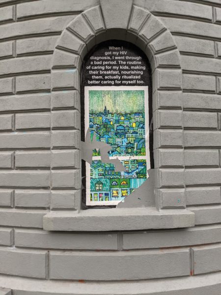 Gray building with castle-style architectural details and a window with a brightly colored, illustrated art piece snugly fit into the window frame, that has been slashed and ripped up.
