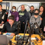 A group of people stand together behind a table with radio equipment