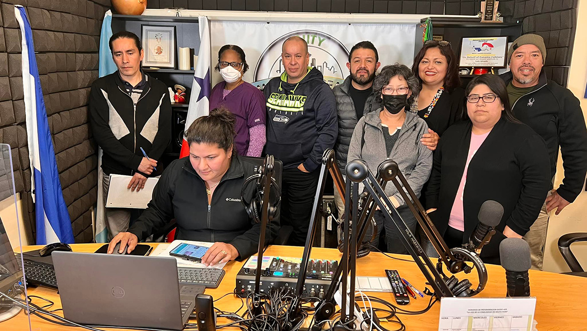 A group of people stand together behind a table with radio equipment