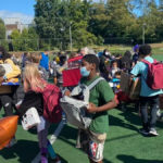 A group of children collecting backpacks and supplies at a back-to-school supply giveaway