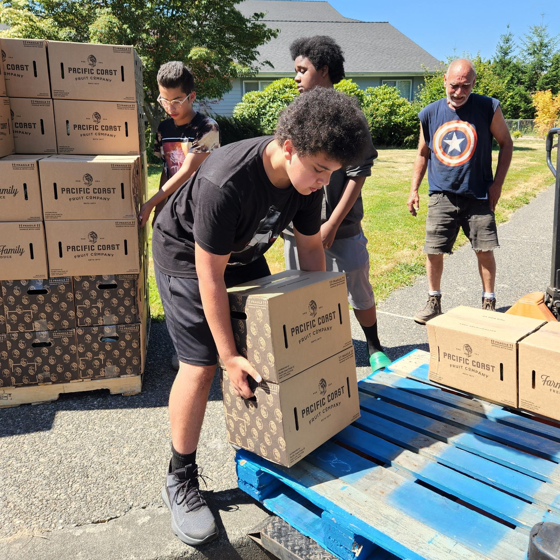 young people lifting boxes of food off wood pallets