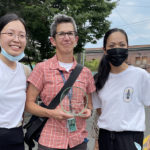 Three people standing together smiling in the Chinatown International District
