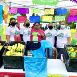 5 people in t-shirts that read "urban Fresh Food Collective" standing behina table filled with produce at an outdoors market