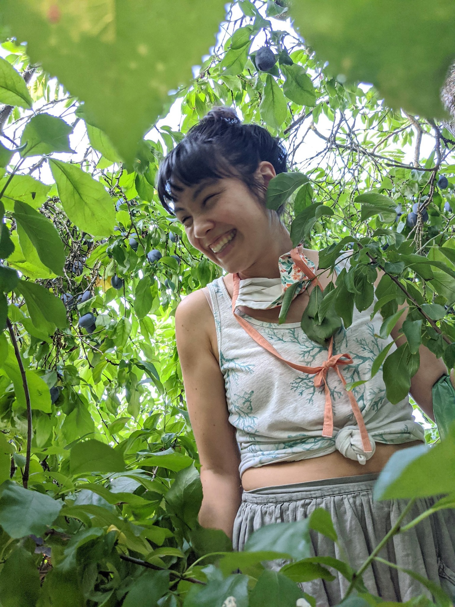 A Taiwanese American woman smiling and standing amongst leaves 