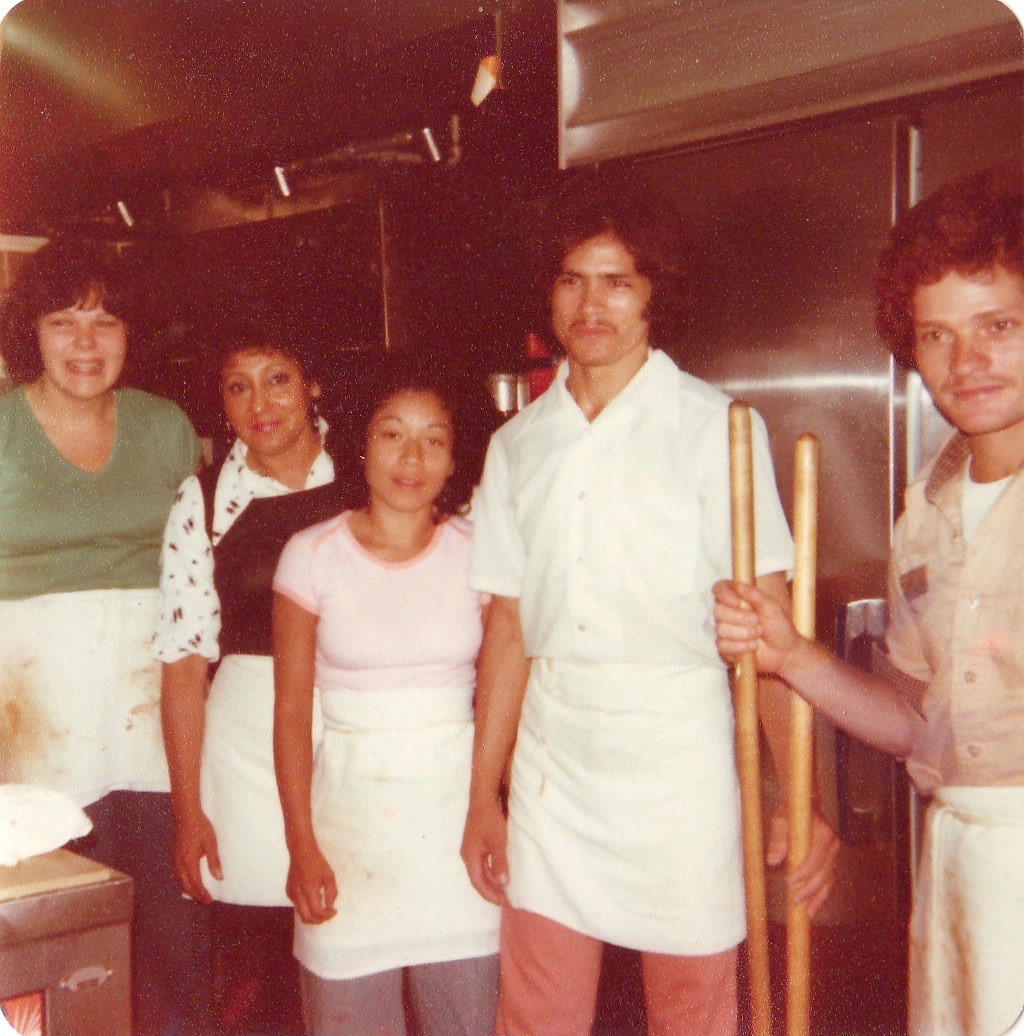 Five people standing in the kitchen of a restaurant