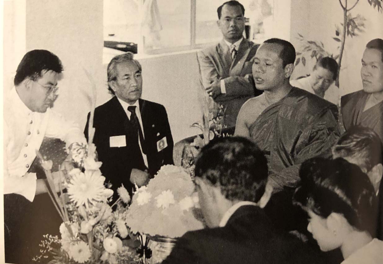 A black and white photo of a group of people sitting around a visiting Laotian prince.