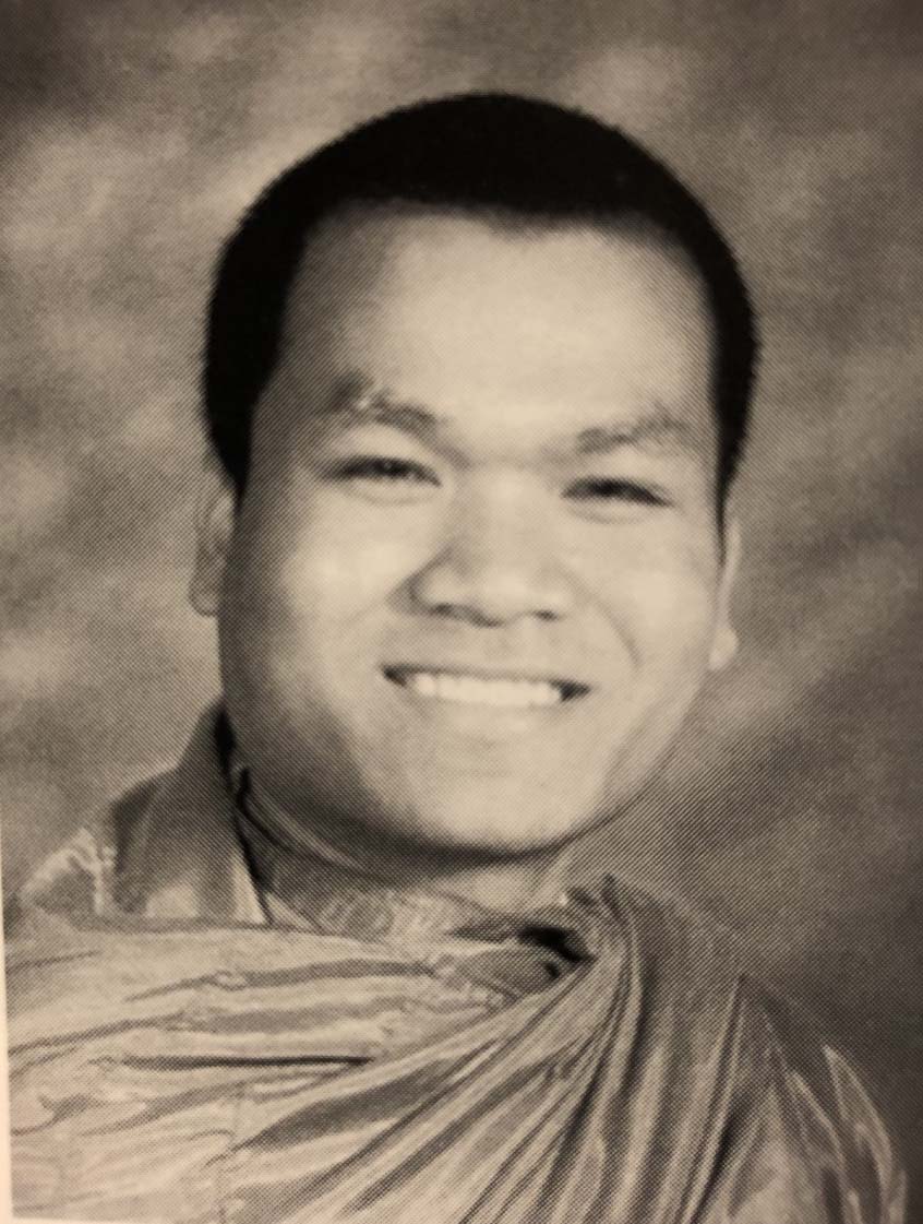 A high school photo of Von, a young monk wearing his traditional robes.