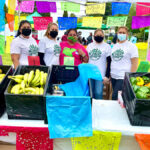 5 people in t-shirts that read "urban Fresh Food Collective" standing behind a table filled with produce at an outdoors market