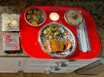 A red tray holding three plates, one large and two smaller, with an array of homecooked food. 