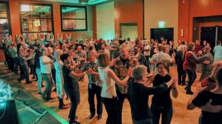 dozens of couples dancing in a large ballroom.