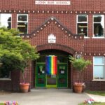 Old-fashioned brick school facade with a rainbow pride flag hanging in front.