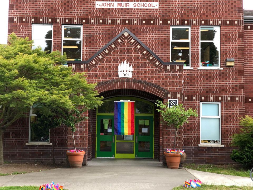 Old-fashioned brick school facade with a rainbow pride flag hanging in front.
