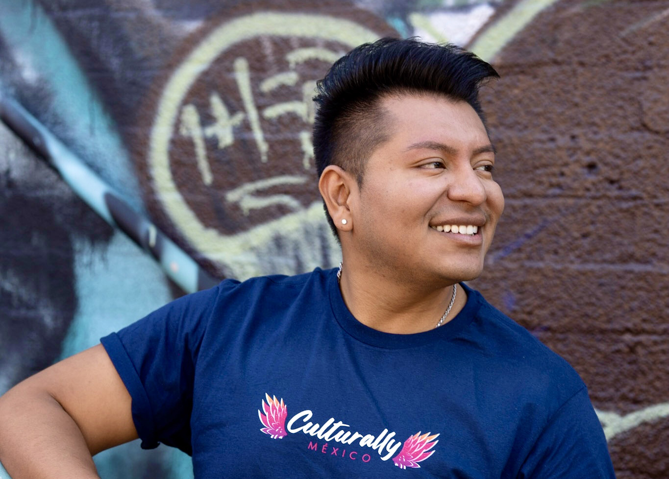 Ray Corona smiles wearing a Culturally Travel T-shirt.