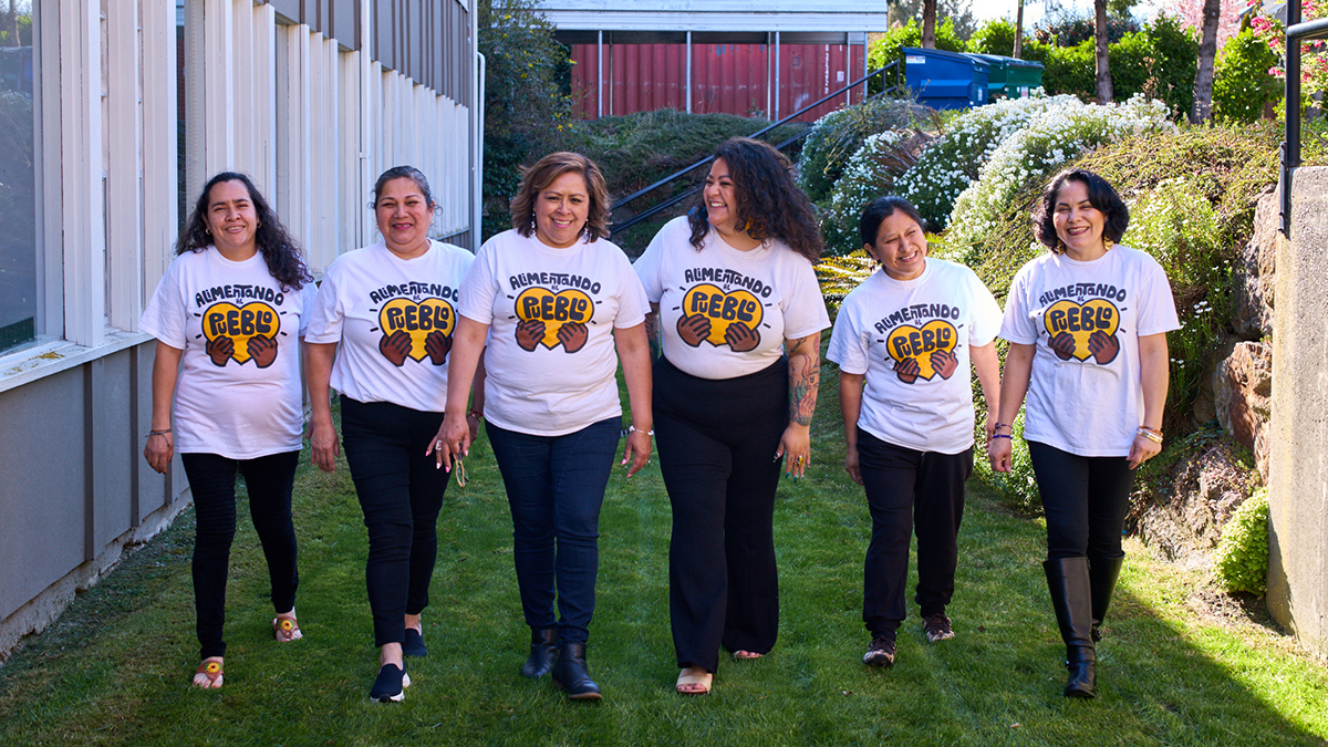 Six Latina women standing in a line wearing white t-shirt that say 