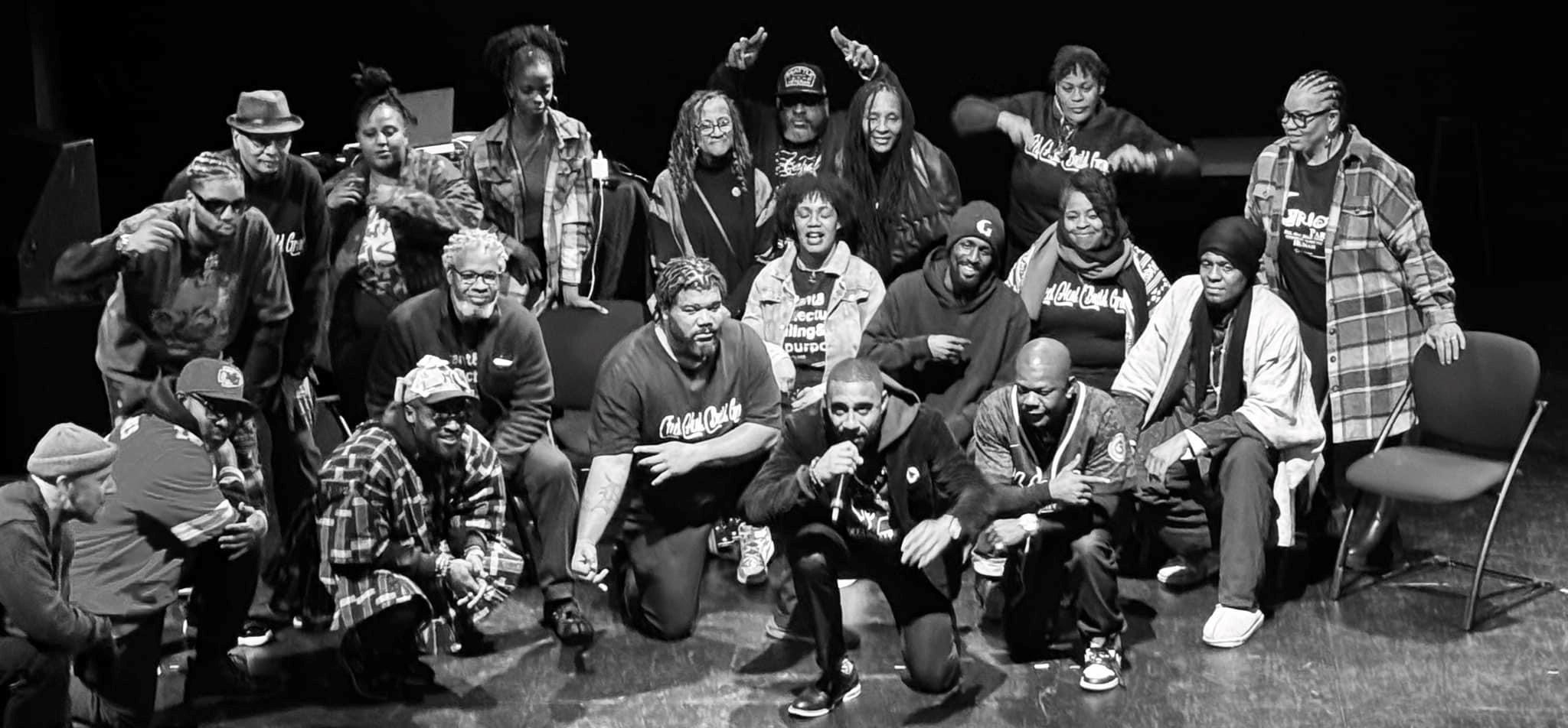 A group of performers gathered together for a black and white photo.