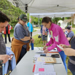 People standing under a tent with notebooks and radios.