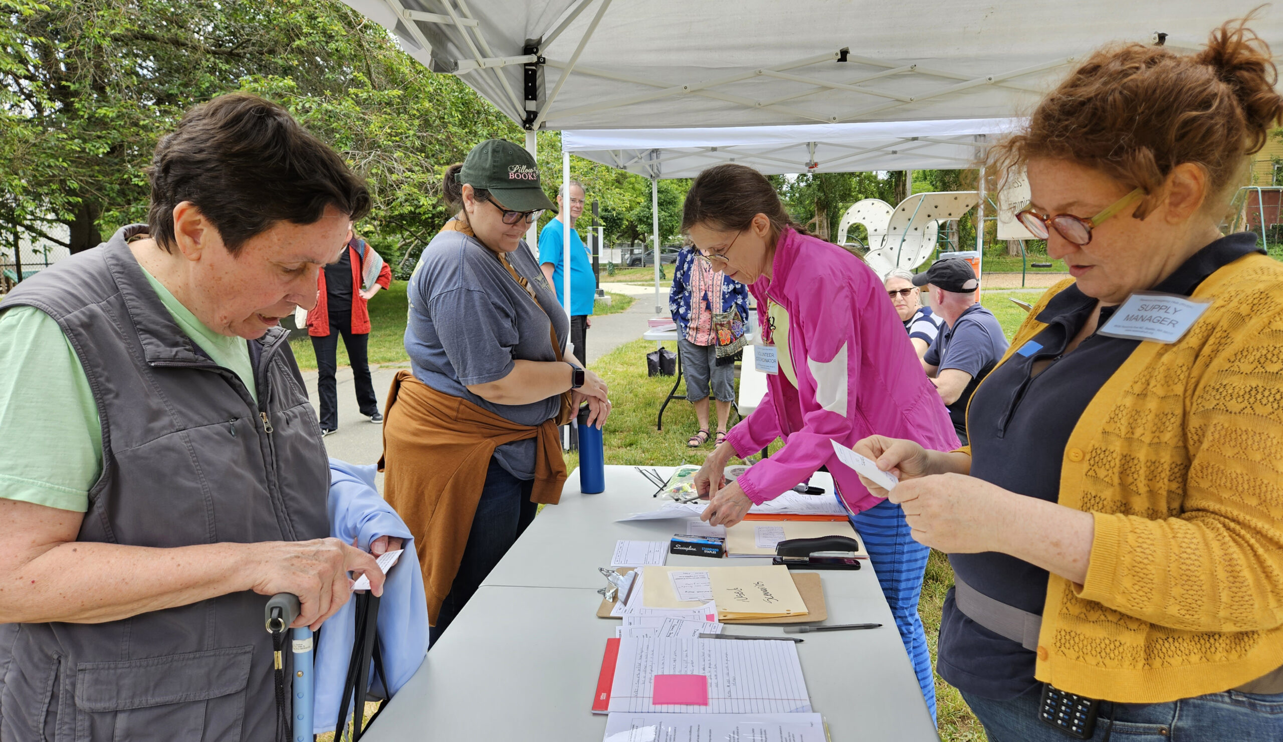 People standing under a tent with notebooks and radios.