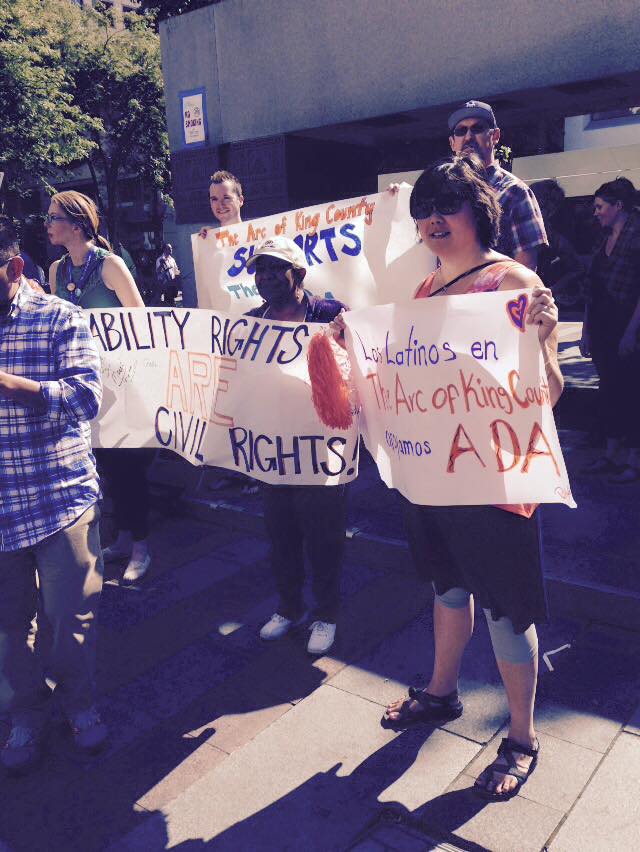 People stand holding signs that read supporting disability rights