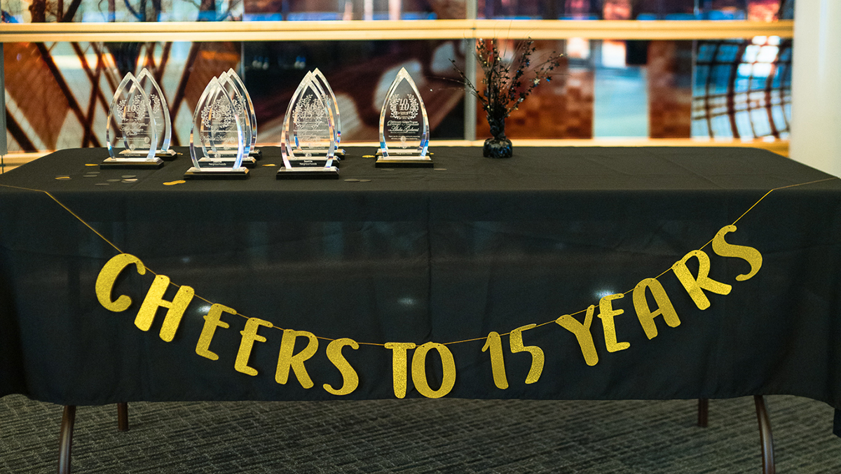 Glass trophies sitting atop a table with black tablecloth and banner that reads 