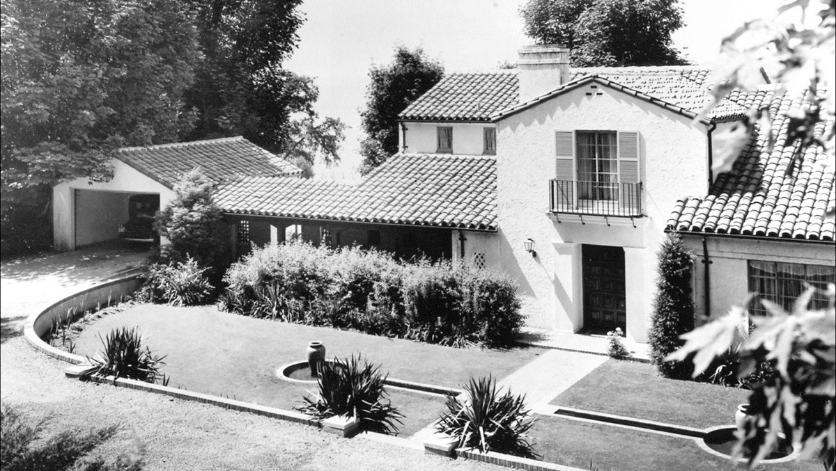 Black and white photo of a two story house and detached garage with ceramic shingles