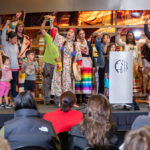 A group of Indigenous People singing and playing drums on a stage in front of an audience.