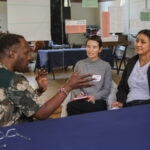 Three people sitting next to a table engaged in conversation