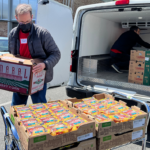 A person unloading boxes of food out of a back of a vehicle