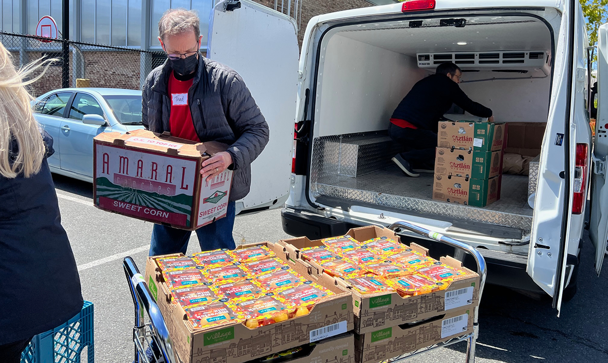 A person unloading boxes of food out of a back of a vehicle