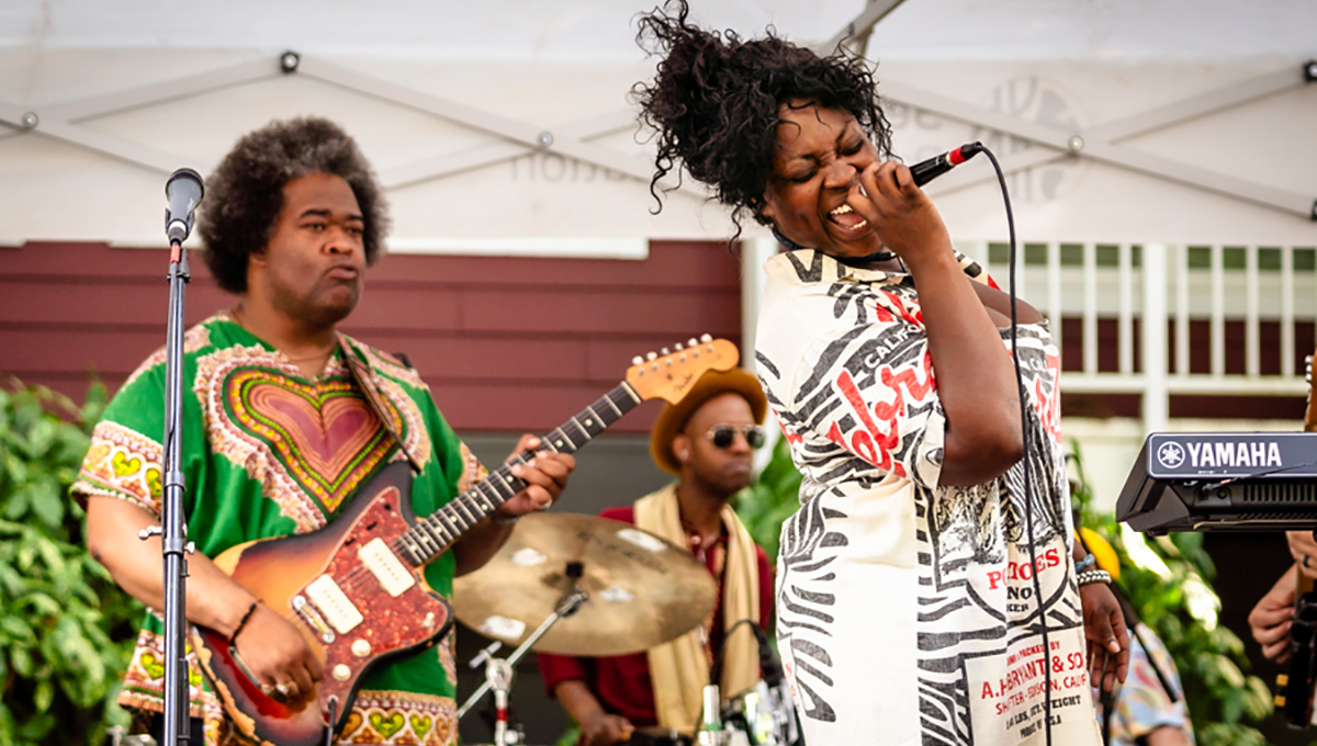 A guitar player and a singer shown mid-performance on a stage
