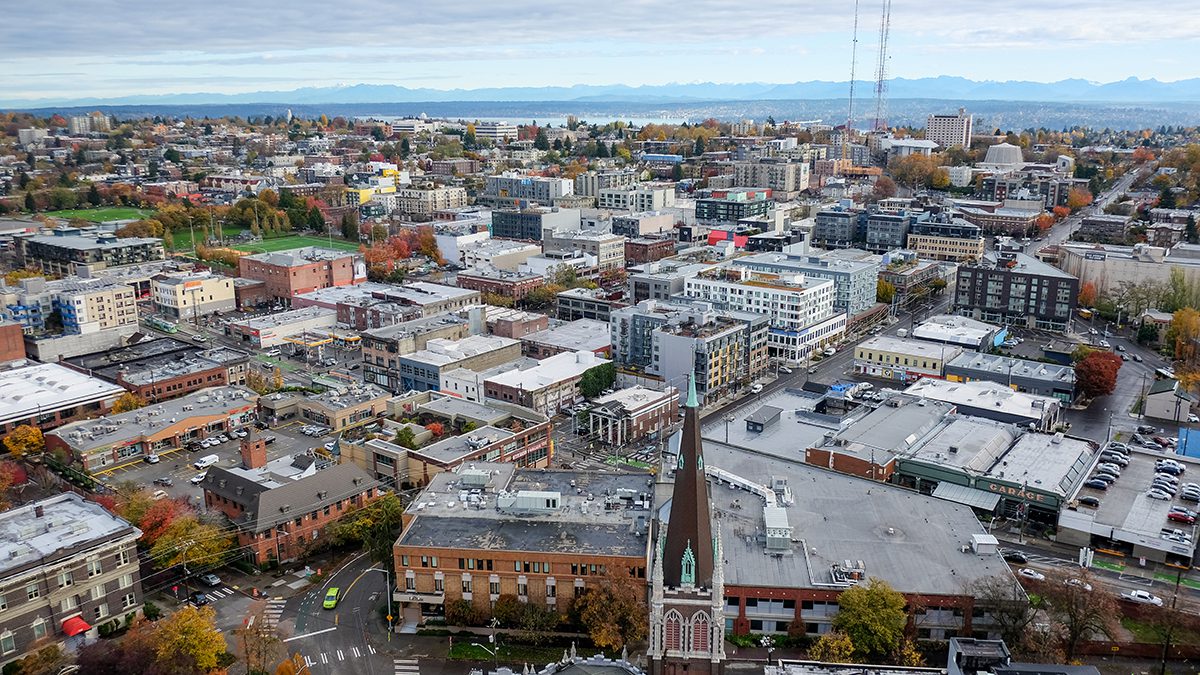 An aerial view of a city neighborhood with mutli-level apartment buildings and mountains in the distance.