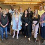 A diverse group 11 people ranging in age and ethnicity standing together smiling