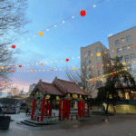 A park in Seattle's Chinatown International District with a pergola in the center and yellow and red lantern lights strung across the courtyard