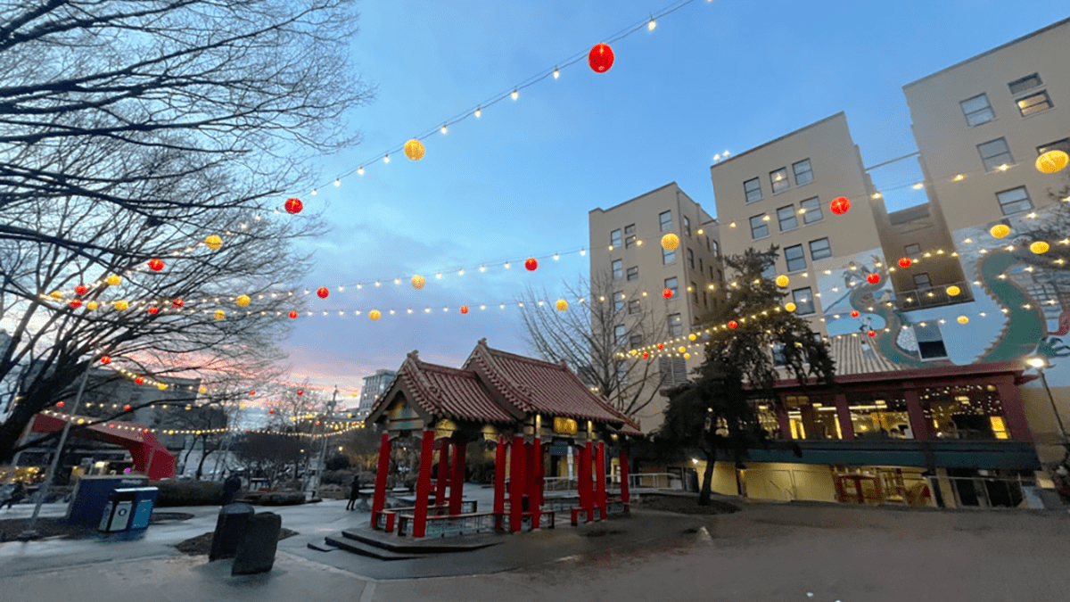 A park in Seattle's Chinatown International District with a pergola in the center and yellow and red lantern lights strung across the courtyard