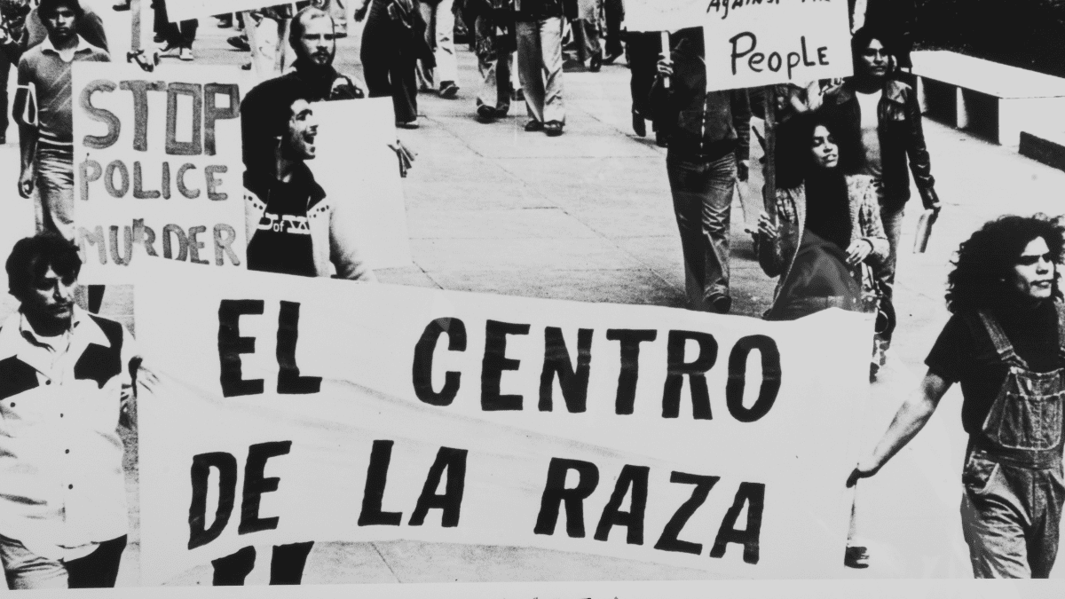 A black and white photos of people marching down the street holding a banner that says