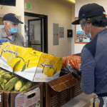 Two people organizing boxes of food in a kitchen
