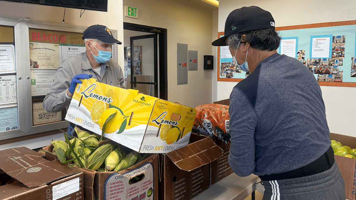 Two people organizing boxes of food in a kitchen