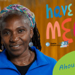Headshot of a Black woman with a colorful headband, blue fleece shirt, and dangly earrings. Colorful text reads "Have We MEt? Ahoua Koné"